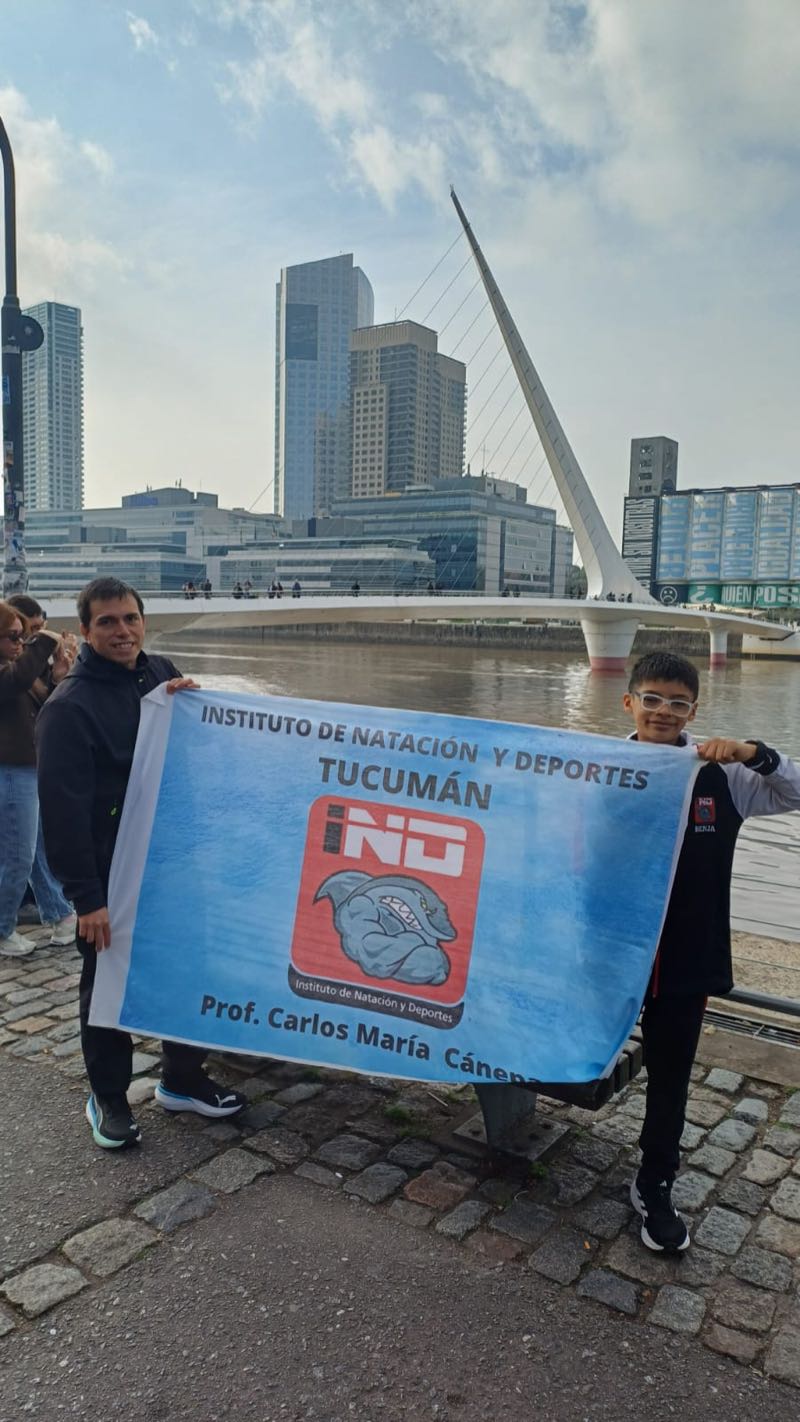 Benjamín y su entrenador con la bandera del Instituto de Natación y Deportes de Tucumán en Puerto Madero, frente al Puente de la Mujer