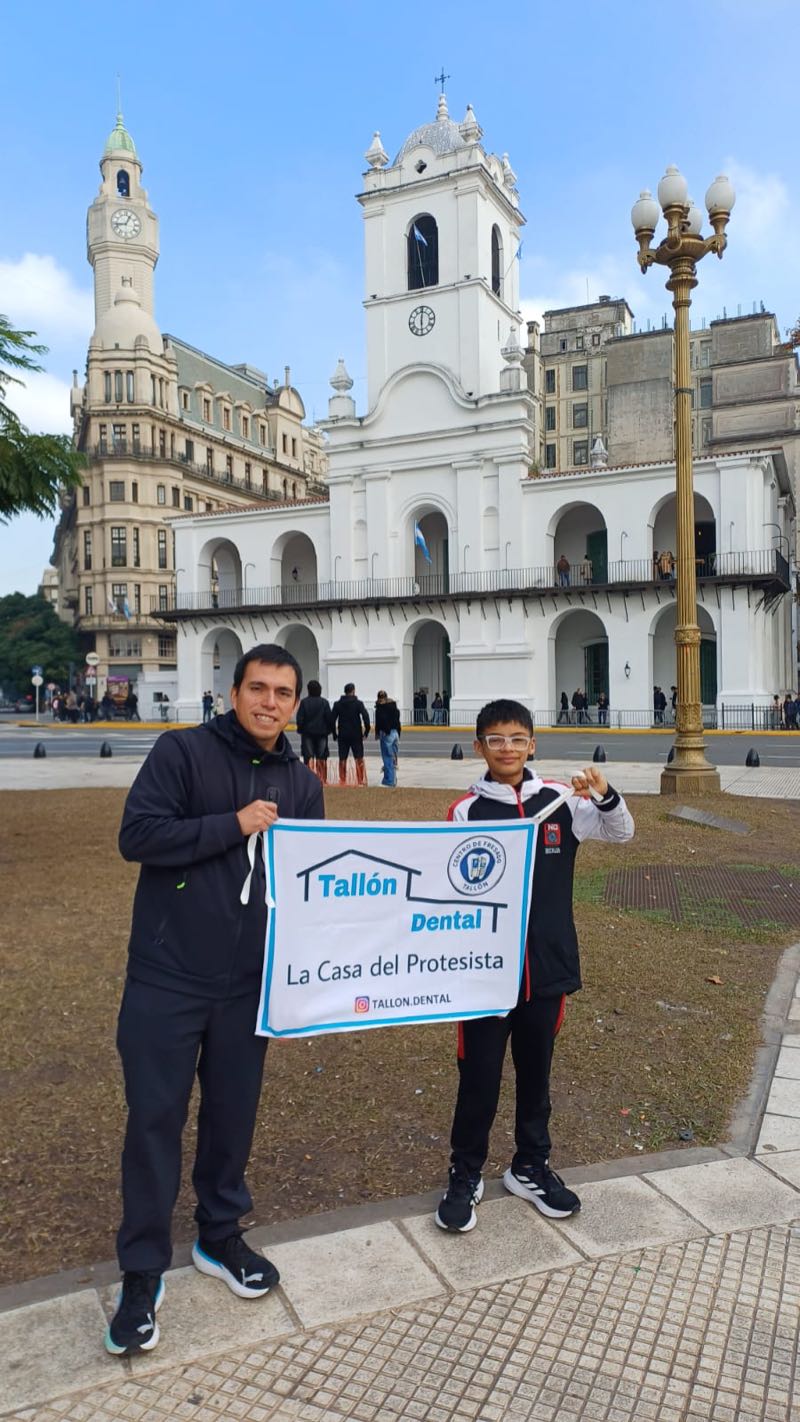 Benjamín y su entrenador con la bandera de Tallón Dental, sponsor, frente al Cabildo de Buenos Aires